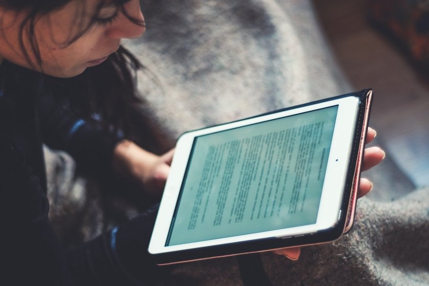 Frau mit Tablet in der Hand liest einen Text (öffnet Vergrößerung des Bildes)
