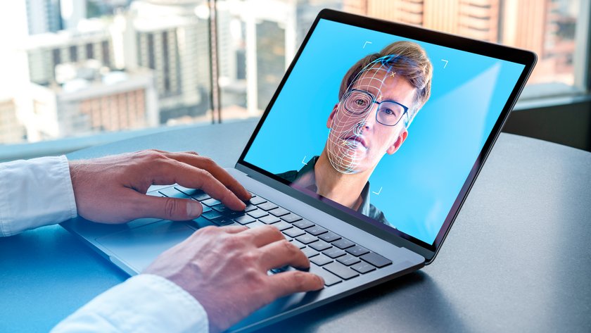 Businessman using laptop with biometric scanning hologram, face swapping
