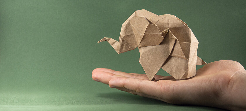 Schmuckbild: Hand hält einen Origami-Elefanten