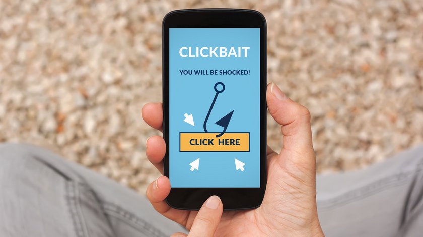 Hands holding smart phone with clickbait concept on screen