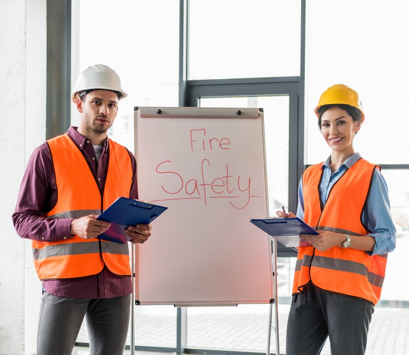 selective focus of fireman standing near attractive coworker near white board with fire safety lettering (opens enlarged image) (opens enlarged image)