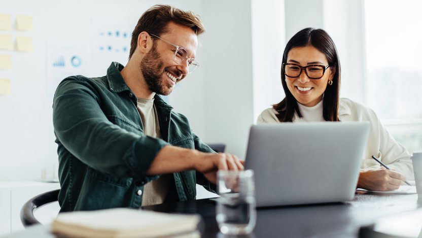 Two business people using a laptop together in an office