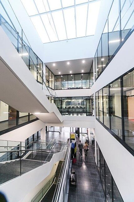Blick in das moderne und helle Treppenhaus der Neubaus der HNU mit Glasdecke