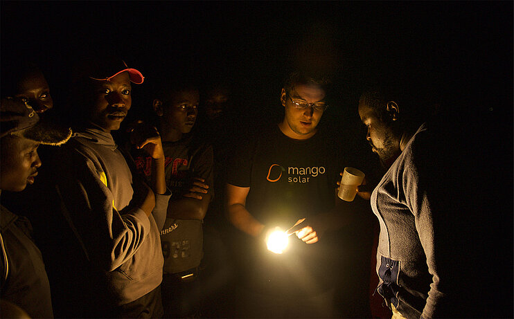 mango solar CEO Danny Friedrich präsentiert mehreren Männern die Solarlampe (öffnet Vergrößerung des Bildes)